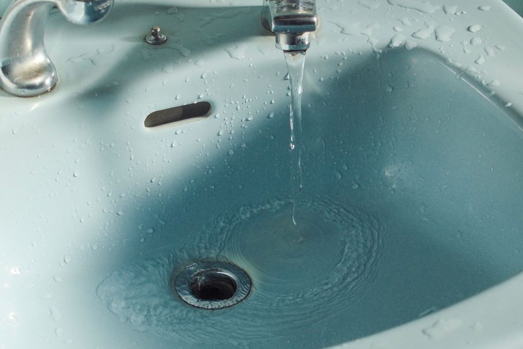 Close-up of water flowing from a faucet into a bathroom sink.