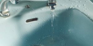 Close-up of water flowing from a faucet into a bathroom sink.
