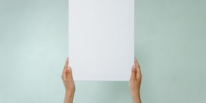 Simple blank canvas held hands on light green background with copy space.